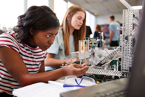 Two young women trying to create something with their hands.